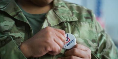 person in army fatigues pinning on an i-voted badge